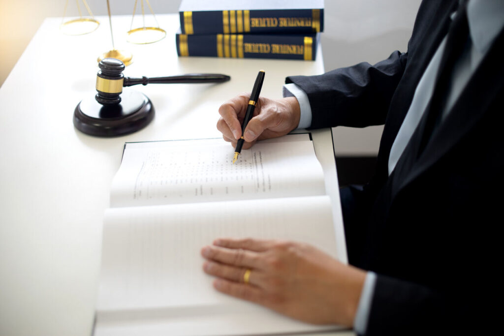 Hit and run accident attorney reviewing legal documents at desk with judge's gavel, scales of justice, and law books.
