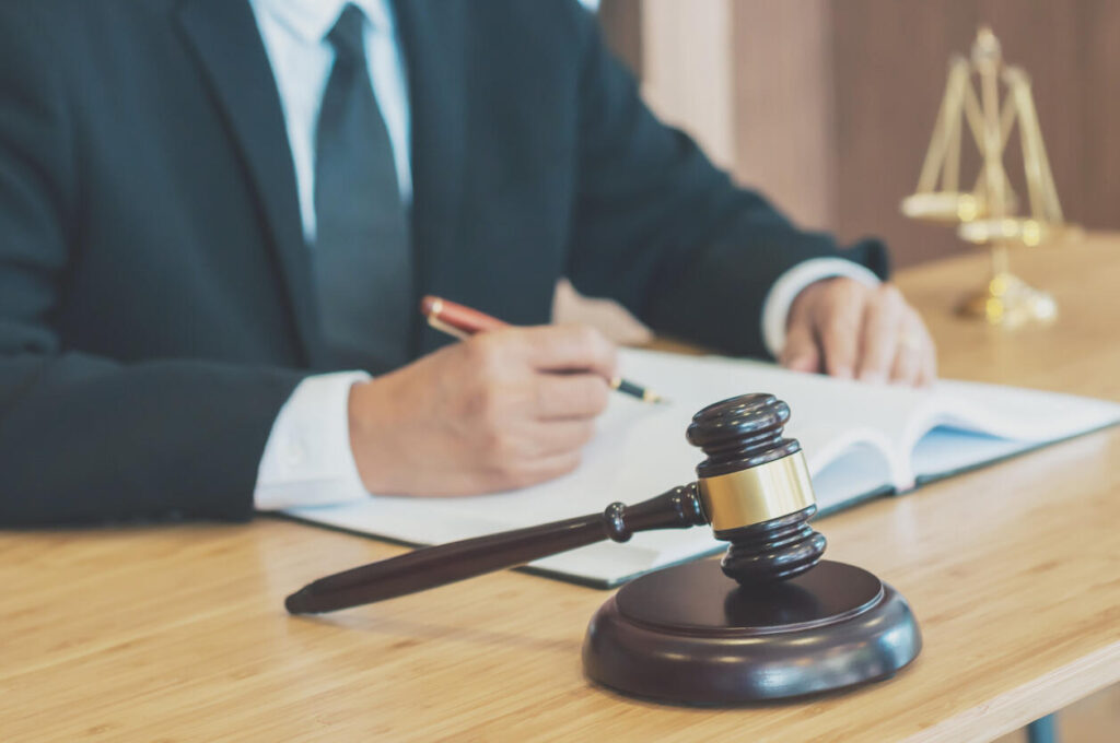 T-Bone accident attorney signing legal documents at desk with judge's gavel and scales of justice in background.