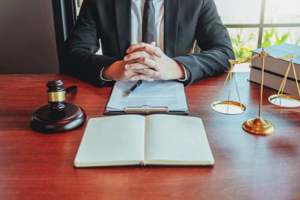 Whiplash injury attorneys consulting with client, legal documents, gavel, and scales of justice on wooden desk