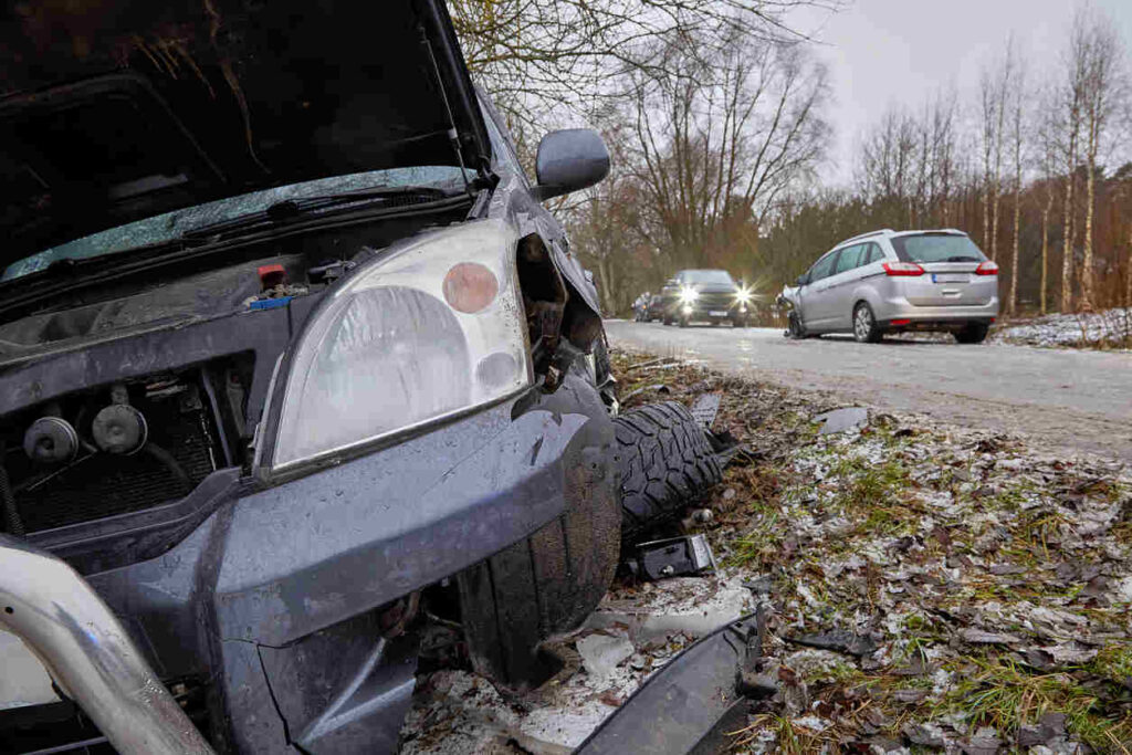 Car accident caused by hazardous road conditions, vehicle damage, and debris on the road. In need of a lawyer for legal assistance after a crash?